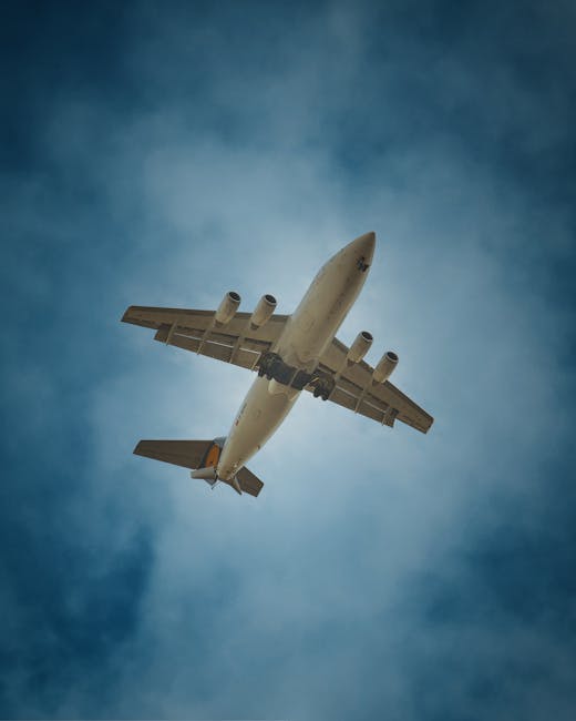 A close-up view of an airplane wing during flight, showing the metallic surface with visible panels and rivets, extending from the bottom left towards the upper right of the image. The wingtip feature